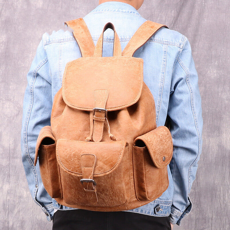 A brown leather backpack with a zipper closure, adjustable straps, and multiple compartments on model.
