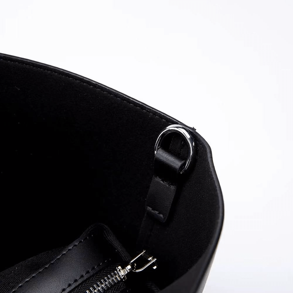 Close-up of a black leather bag with a silver zipper and clasp on a white background