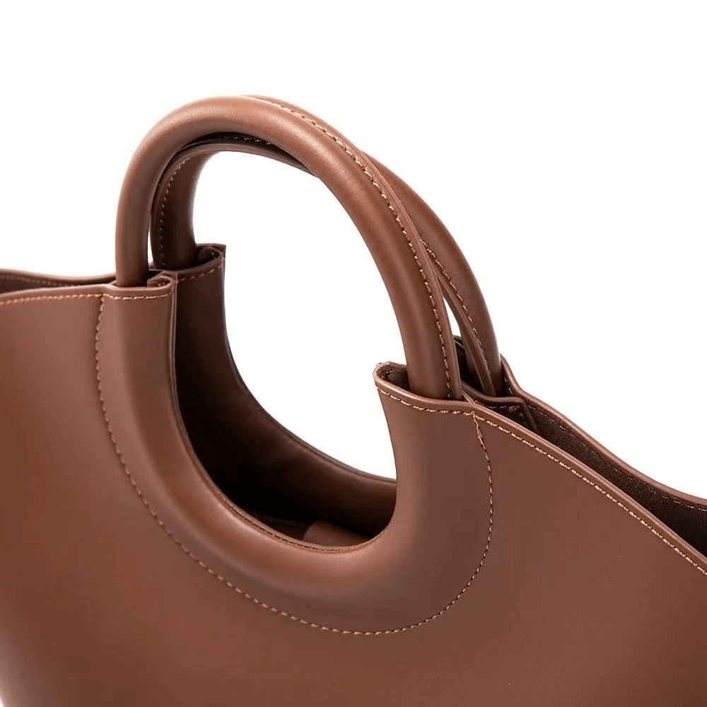 Close-up of a brown leather handbag with a white background