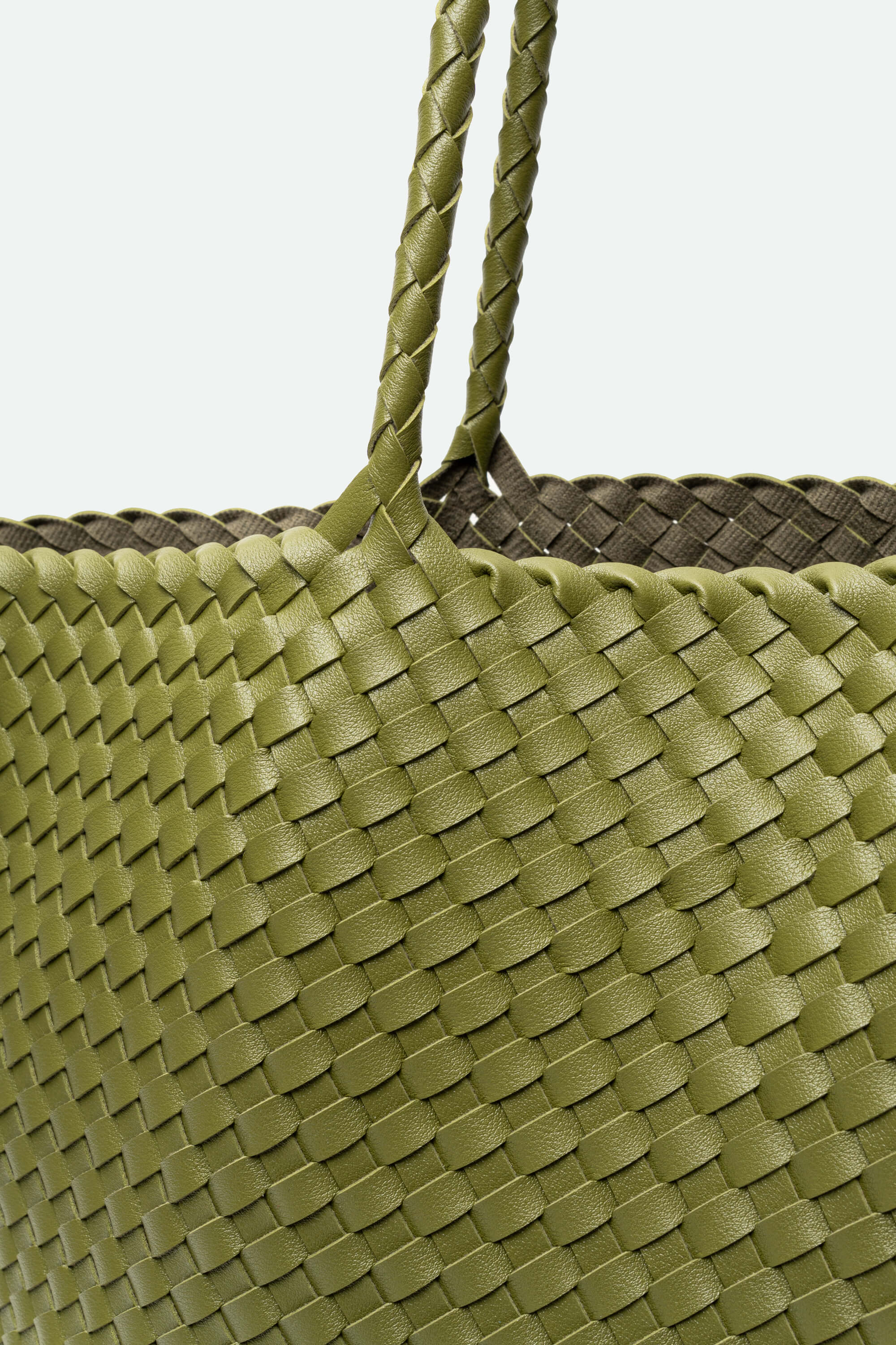 Close-up of a green woven bag with braided handle on a white background