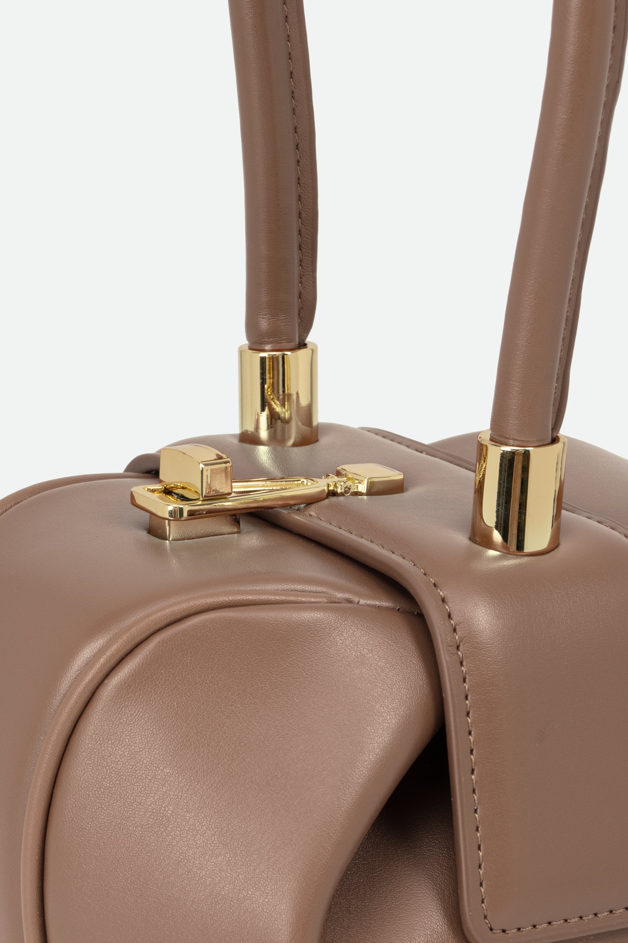 Close-up of a brown leather handbag with gold hardware on a light gray background