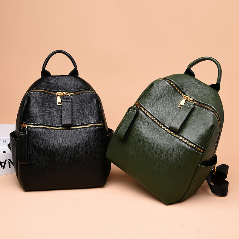 Green and black leather backpack with gold-tone hardware, featuring a front zipper pocket and adjustable straps.