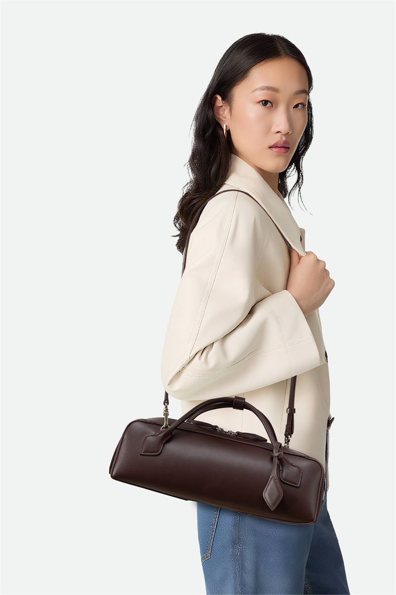Woman holding a brown leather handbag against a white background