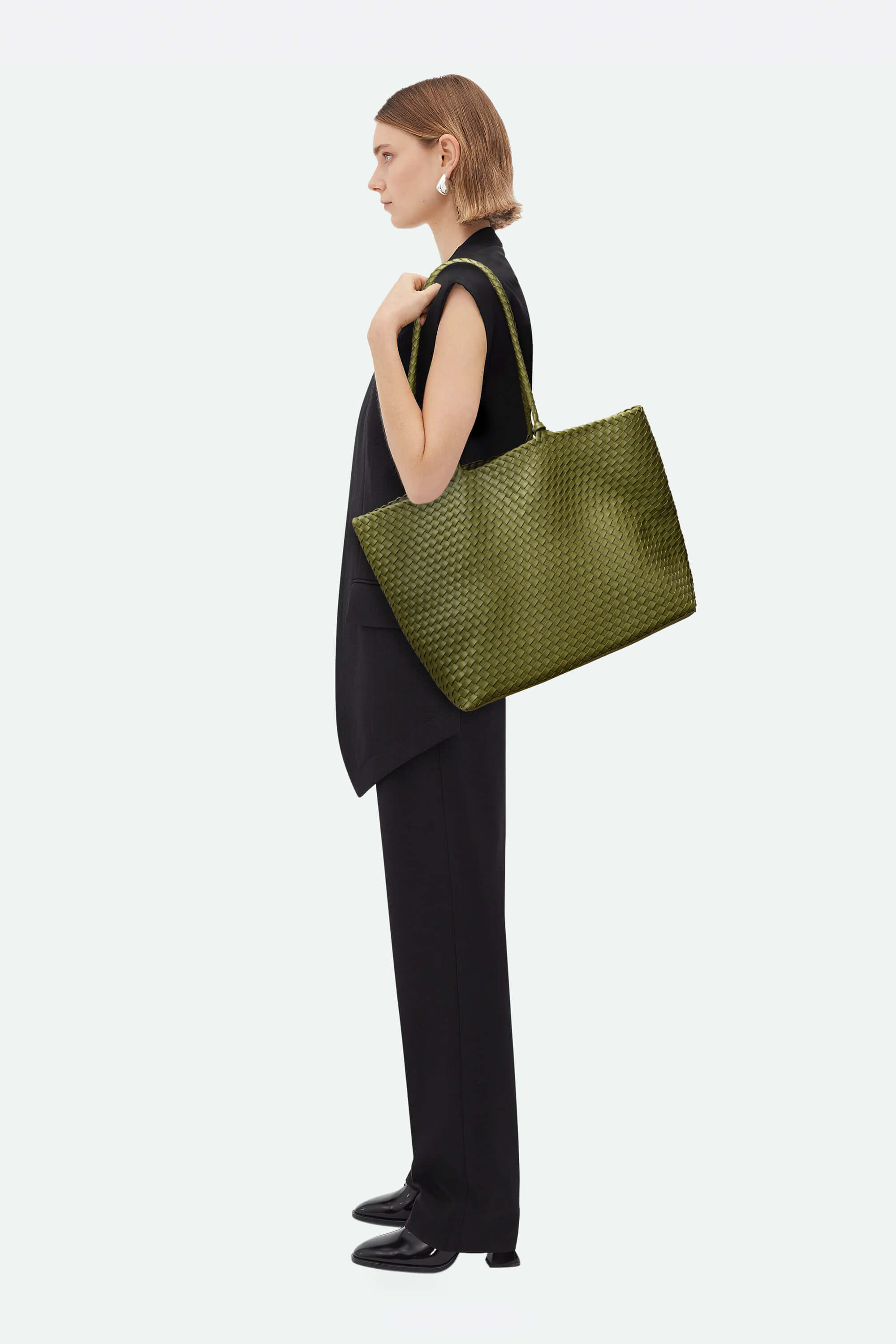 Woman holding a green handbag against a white background
