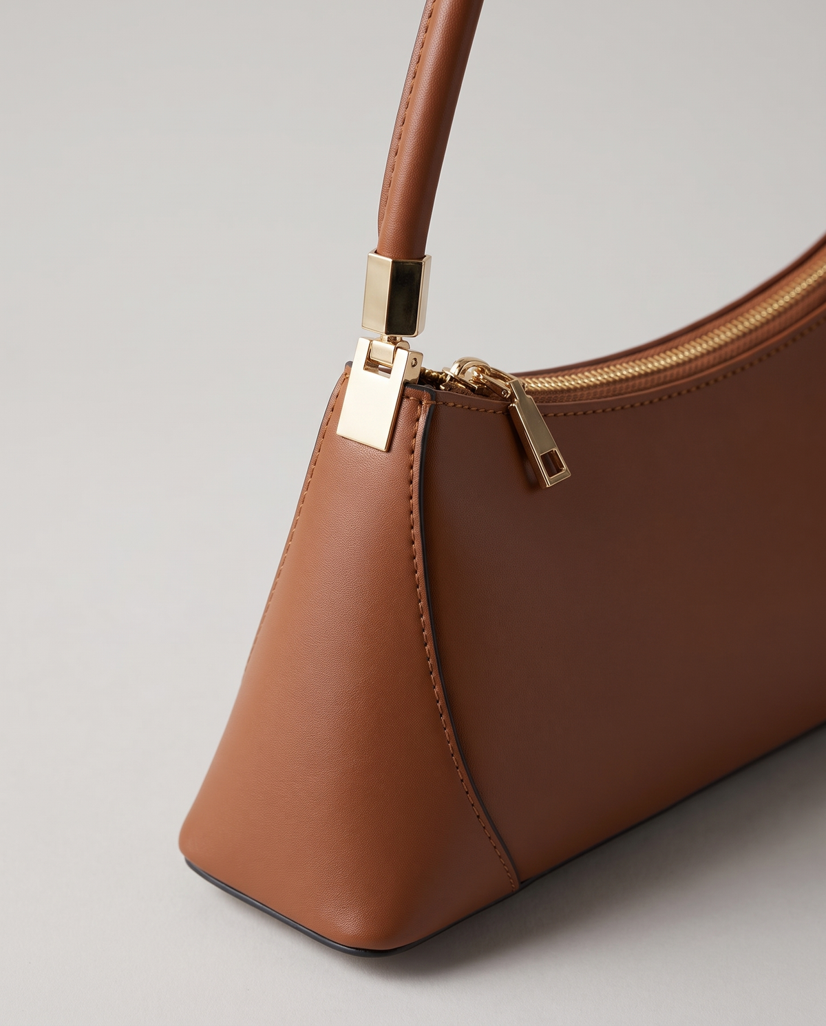 Arc leather shoulder bag in Brown – close-up of the gold strap fitting and zip pull