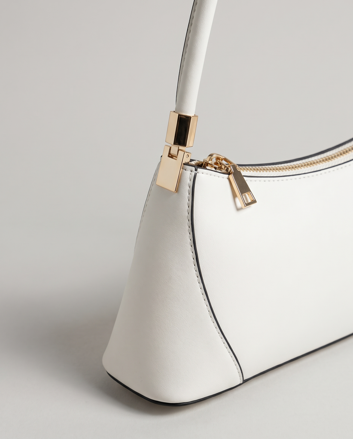 Arc leather shoulder bag in Chalk – close-up of the gold strap fitting and zip pull