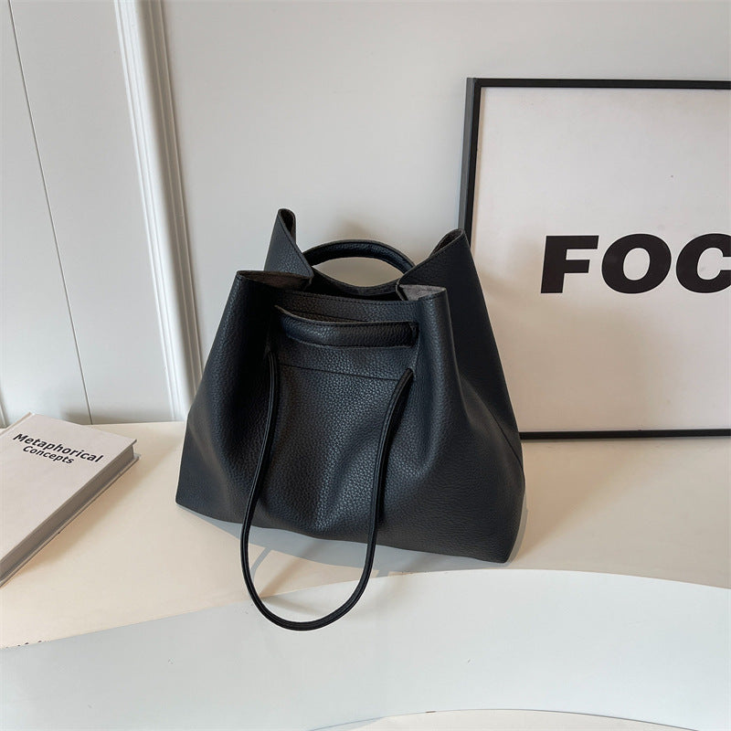 Black leather tote bag on a white surface with a black frame in the background