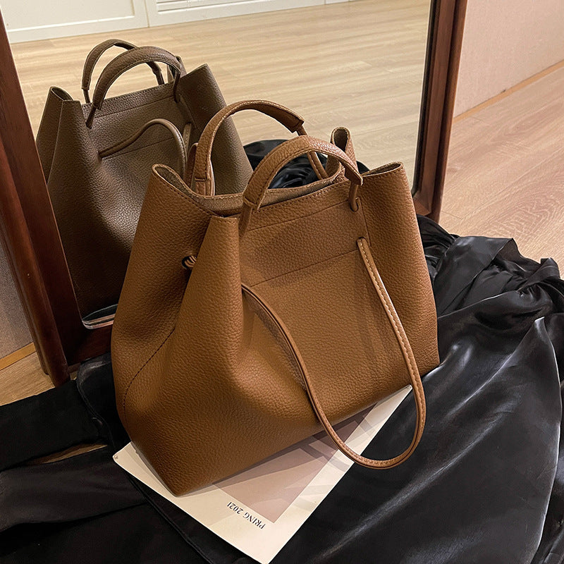 Brown leather tote bag resting on a black cloth in front of a mirror