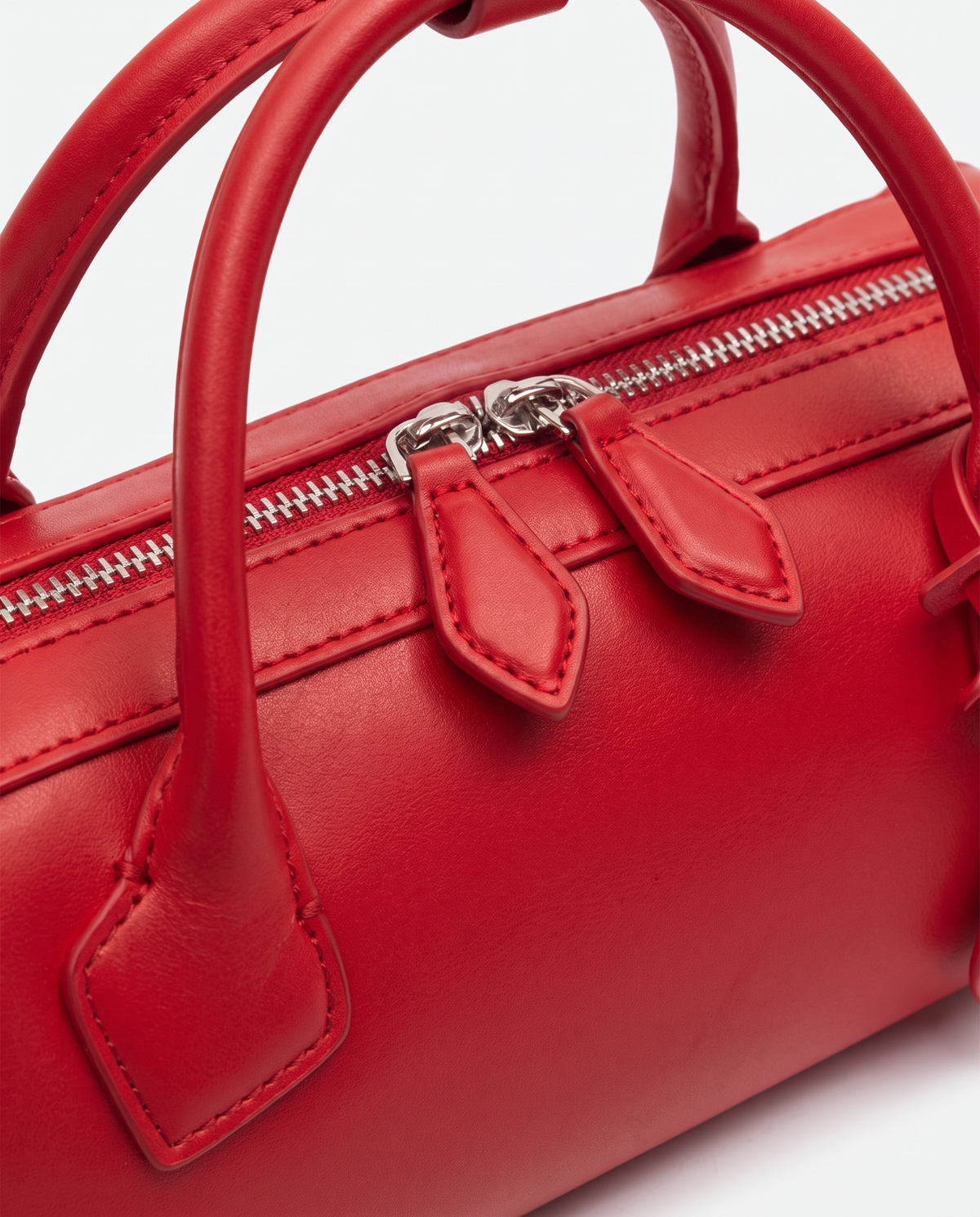 Curve leather barrel bag in Red – close-up of the handle and zip pulls
