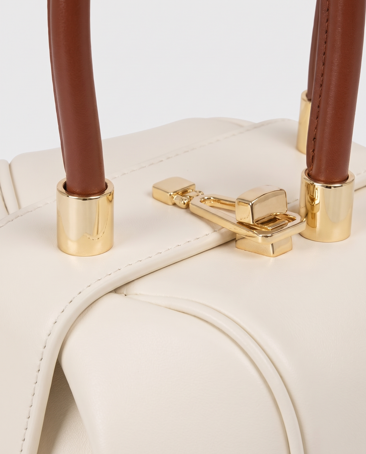 Dumpling Maxi leather top-handle bag in White – close-up of the gold twist-lock and handle fittings