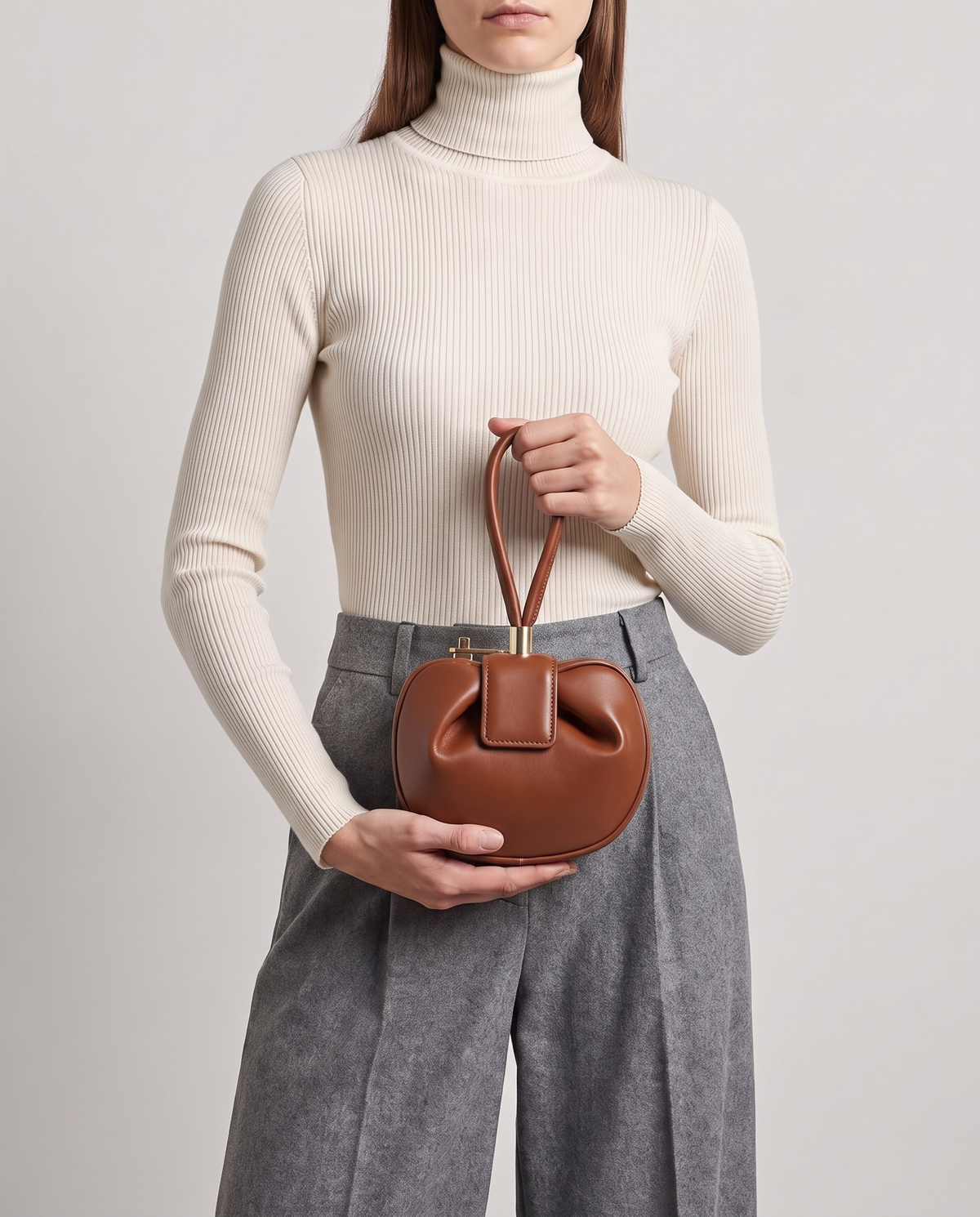 Dumpling Mini leather top-handle bag in Brown – model holding it at the waist