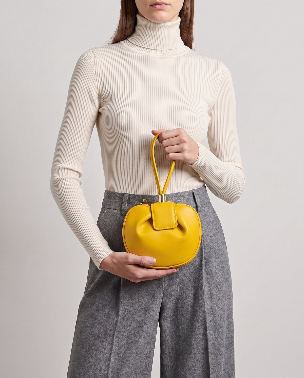 Dumpling Mini leather top-handle bag in Yellow – model holding it at the waist