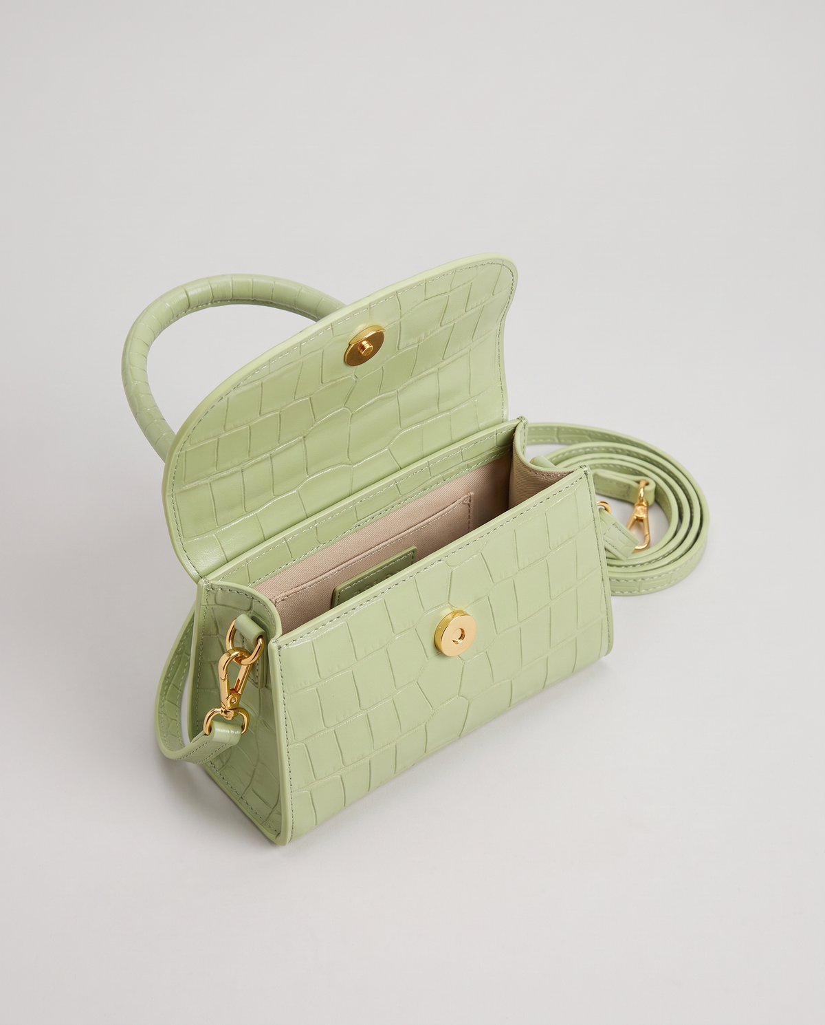 Fern mini croc top-handle bag in Pistachio – flap open, showing the lined interior