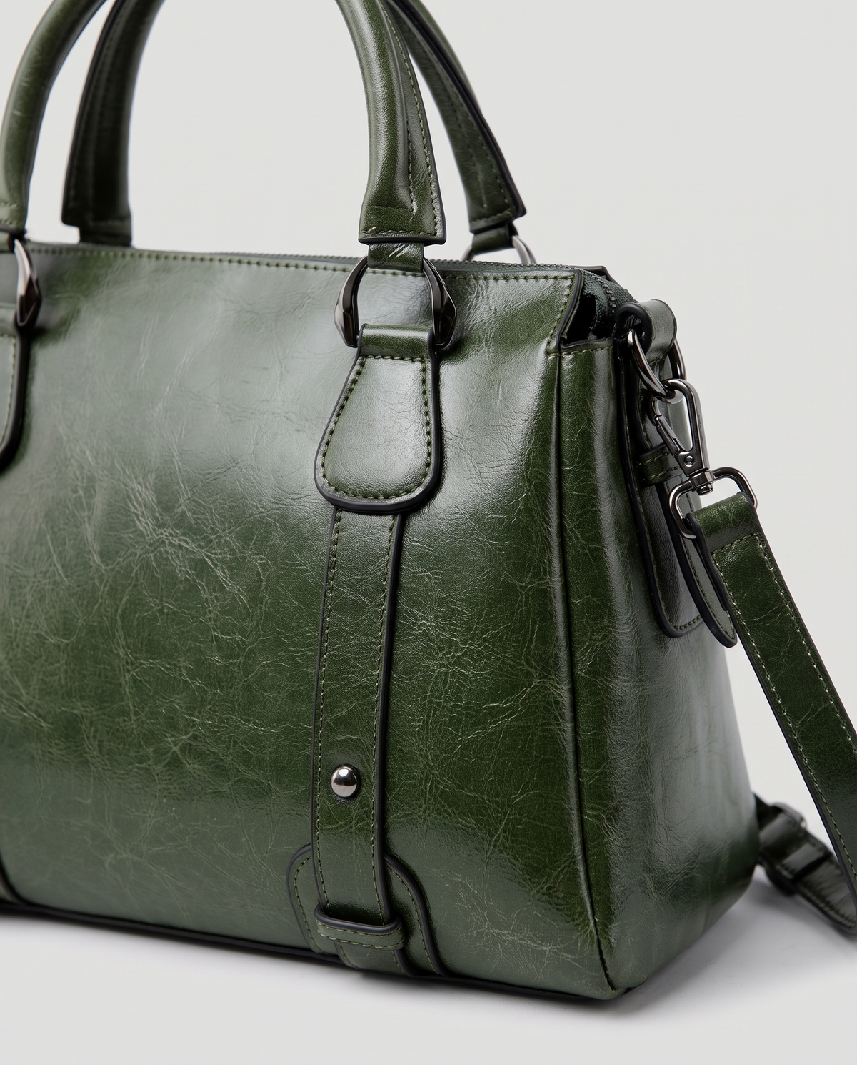 Harlow leather handbag in Green – close-up of the top handle, front strap rivets and side ring