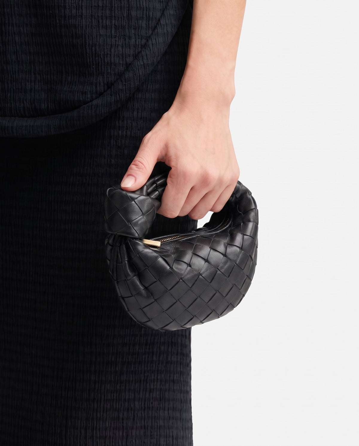 Knot Mini woven leather bag in Black – held in the hand, showing true size