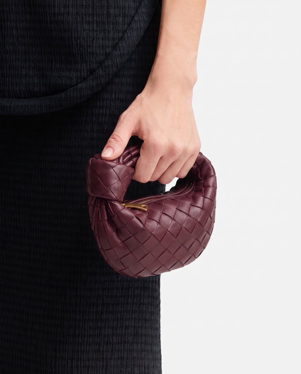 Knot Mini woven leather bag in Bordeaux – held in the hand, showing true size