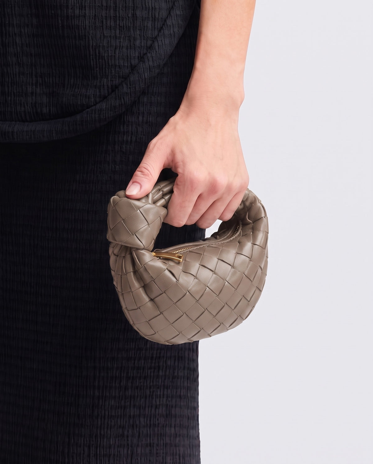 Knot Mini woven leather bag in Camel – held in the hand, showing true size