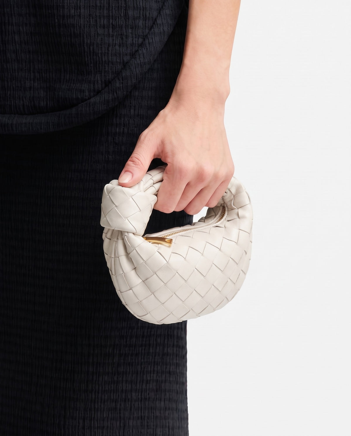 Knot Mini woven leather bag in Chalk – held in the hand, showing true size