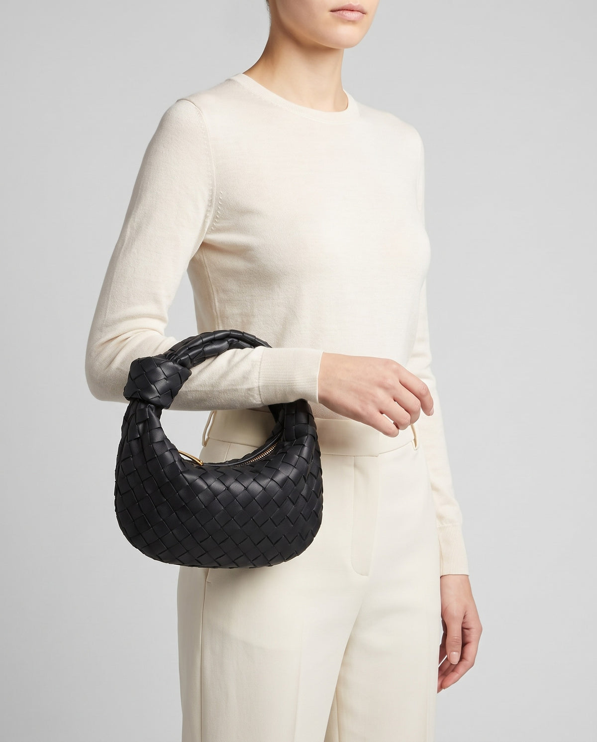 Knot Small woven leather bag in Black – model carrying it by the knotted handle