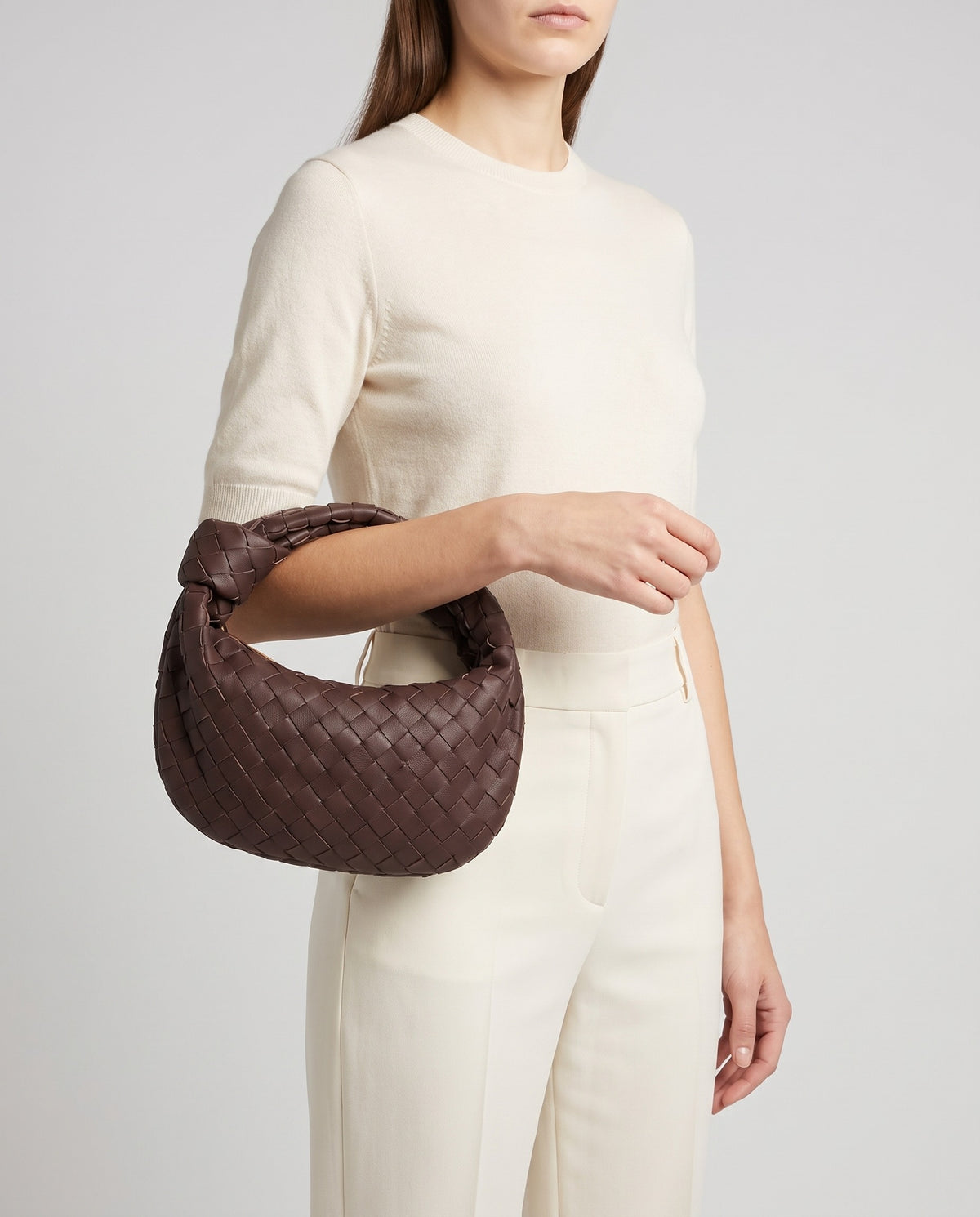 Knot Small woven leather bag in Espresso – model carrying it by the knotted handle