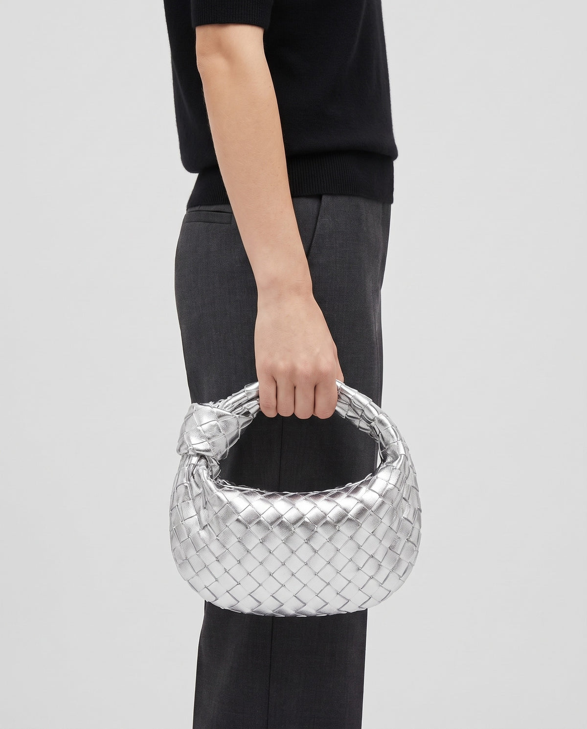 Knot Small woven leather bag in Silver – model carrying it by the knotted handle