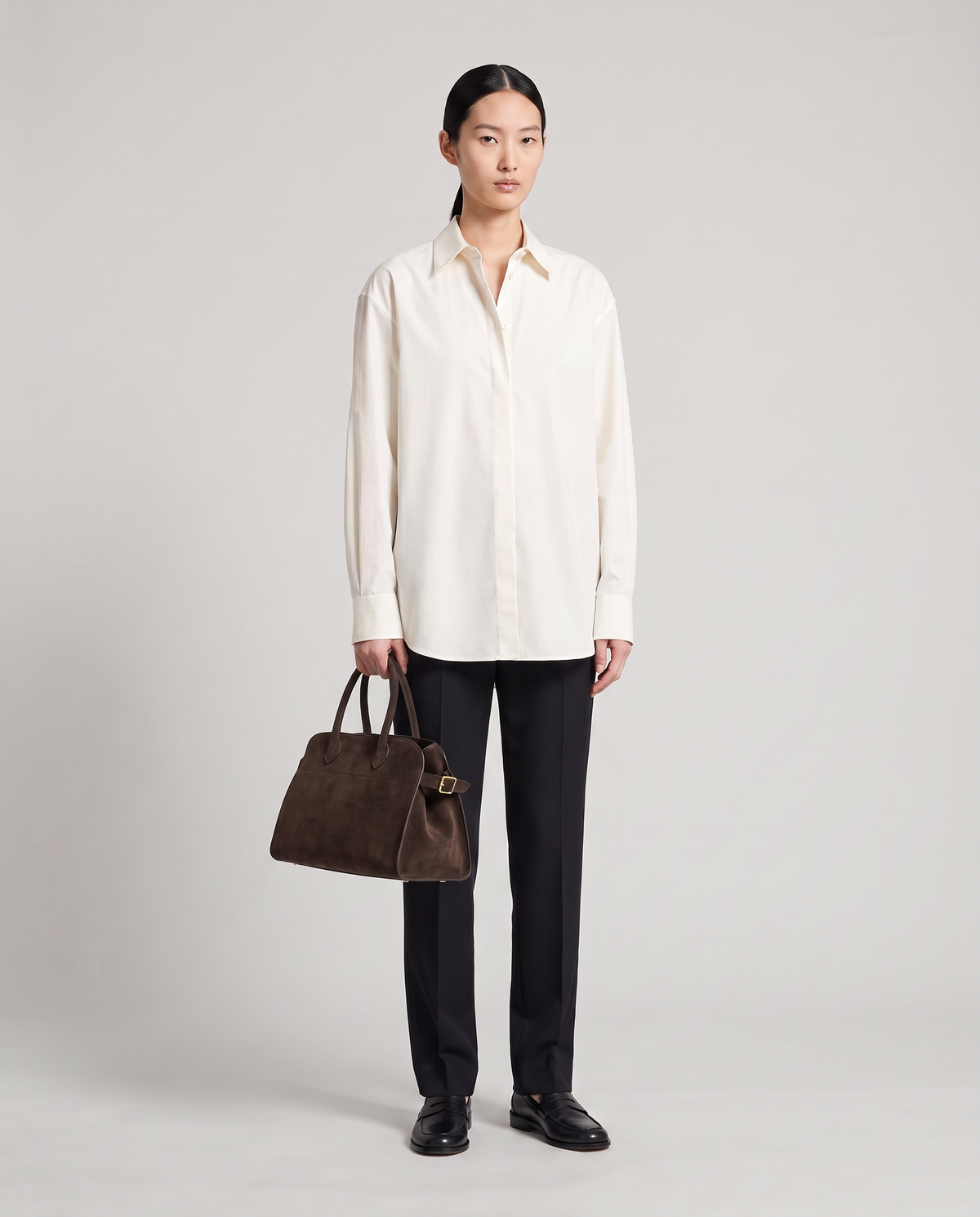Milano Small top-handle bag in Chocolate suede – model holding it by the top handles, full length