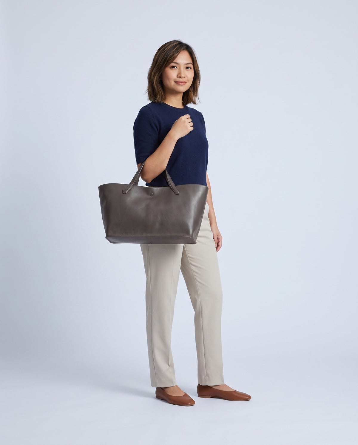 Model carrying the Nube leather tote in Grey – full length