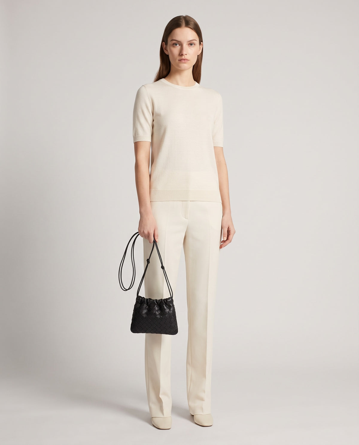 Model holding the Serata woven leather clutch in black – full length