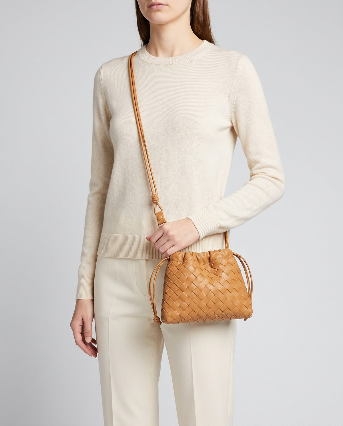 Model wearing the Serata woven leather clutch in Camel crossbody