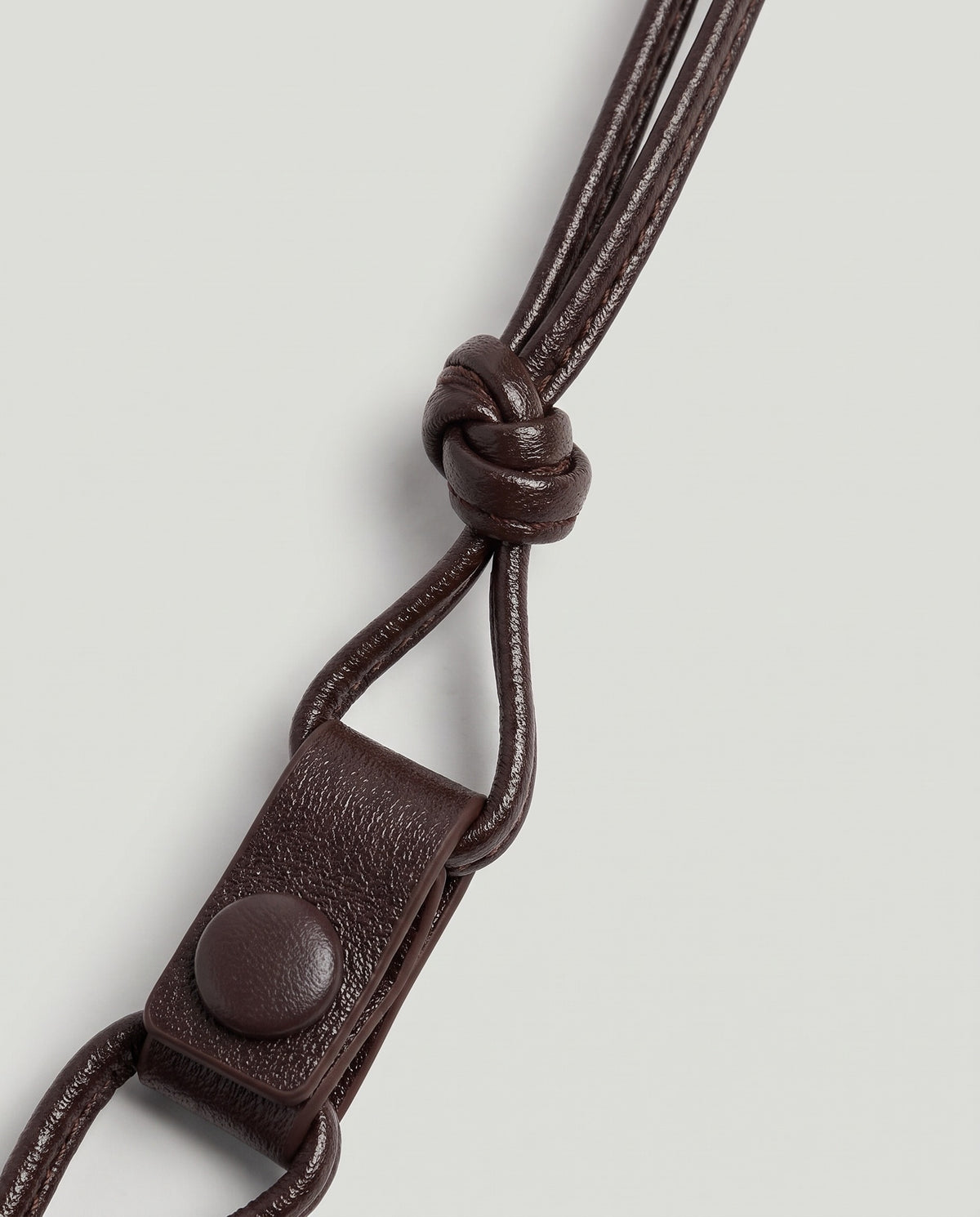 Serata woven leather clutch in Espresso – strap knot and snap tab detail