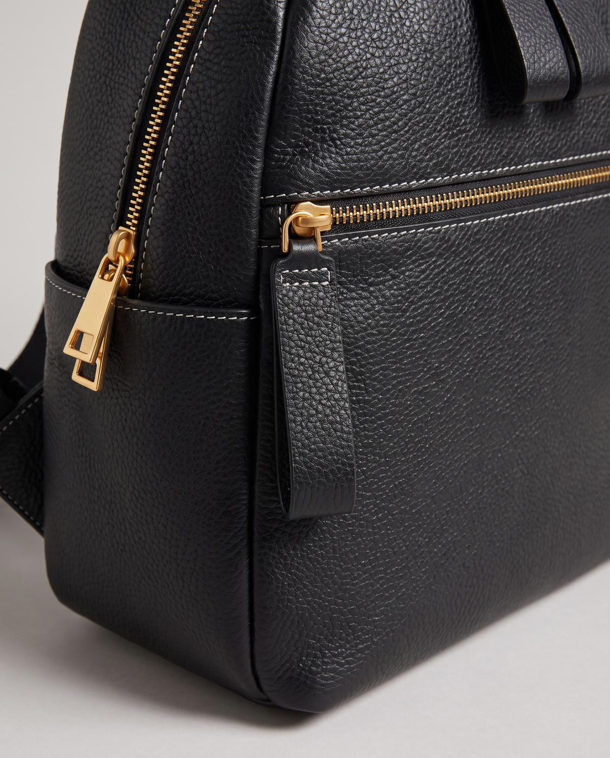 Tab pebbled leather backpack in Black – close-up of the gold zips and pebbled leather