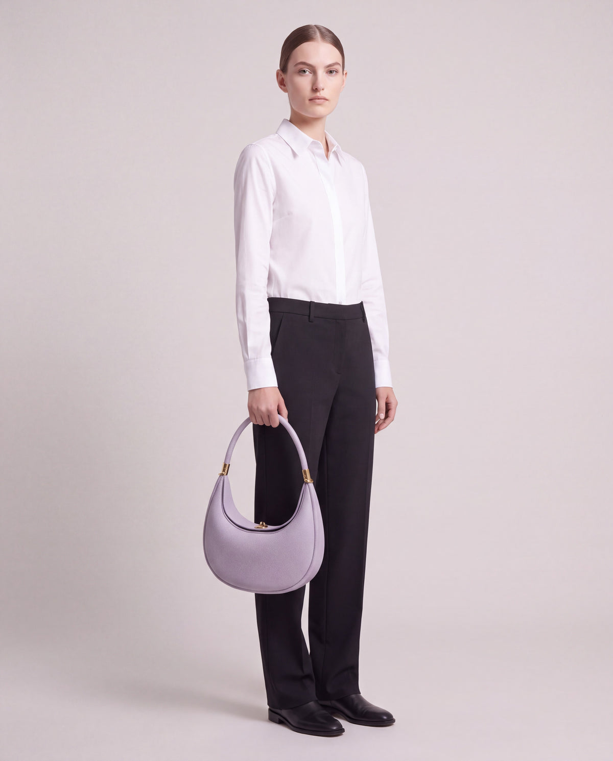 Model carrying the Todi crescent bag in Lavender by the top handle – full-length view