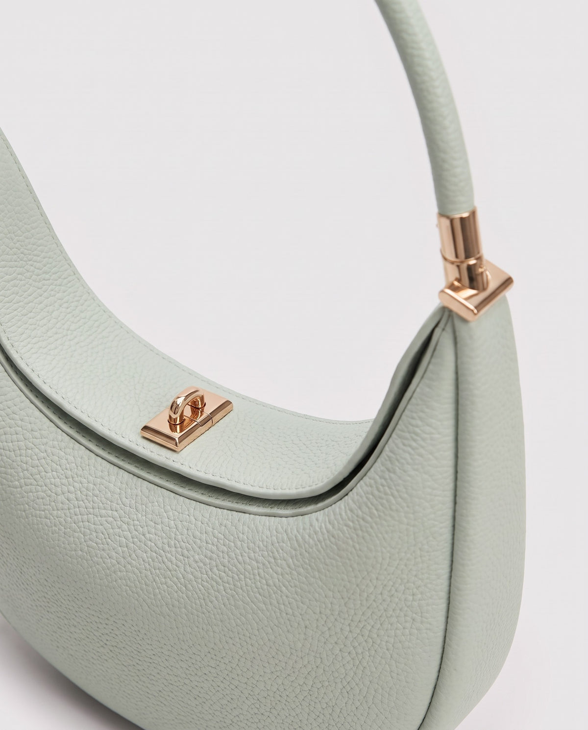 Gold clasp and handle collar detail on the Todi crescent bag in Mint