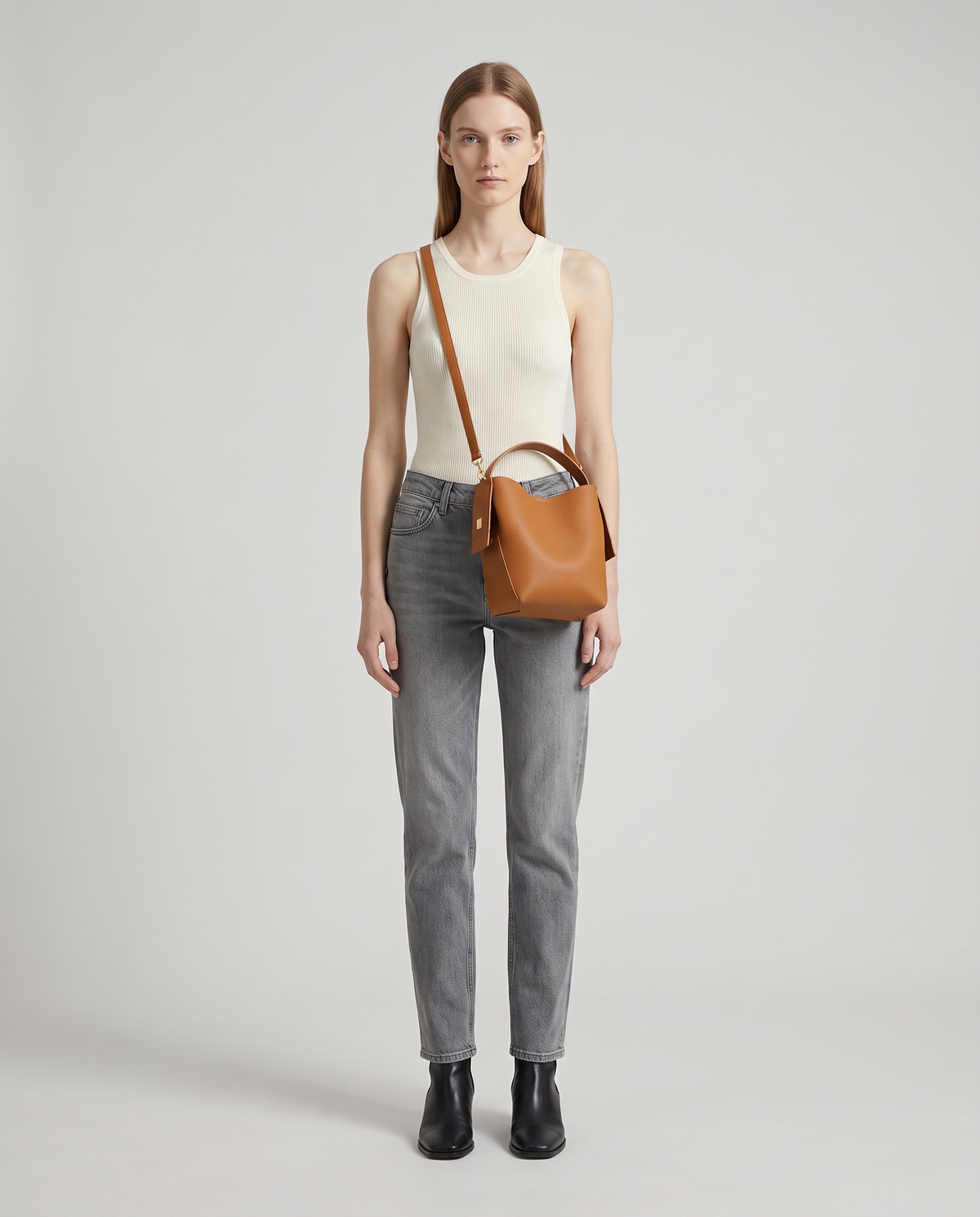 Transit leather bucket bag in Caramel – model wearing it crossbody, full length