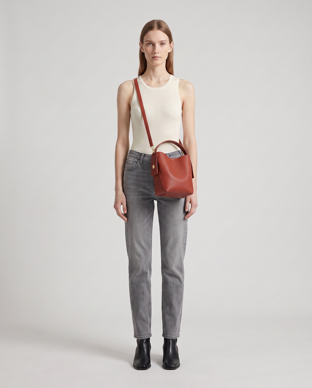 Transit leather bucket bag in Rust – model wearing it crossbody, full length
