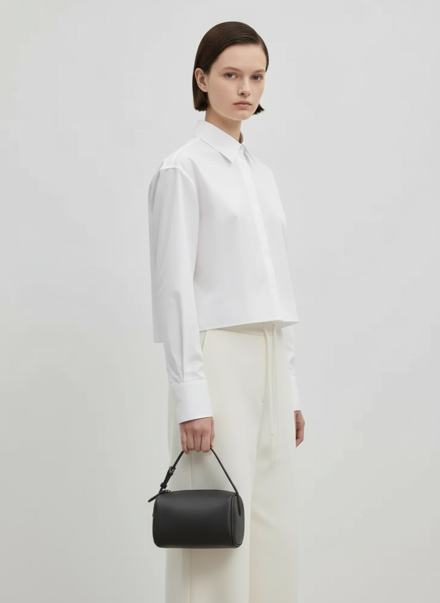 Model carrying the Valentina Roma barrel bag in charcoal leather by its top handle