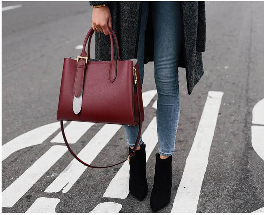 A woman carrying a wine red leather handbag