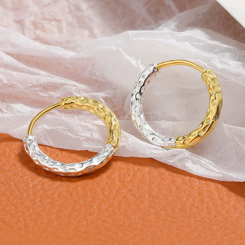 A pair of gold and silver hoop earrings