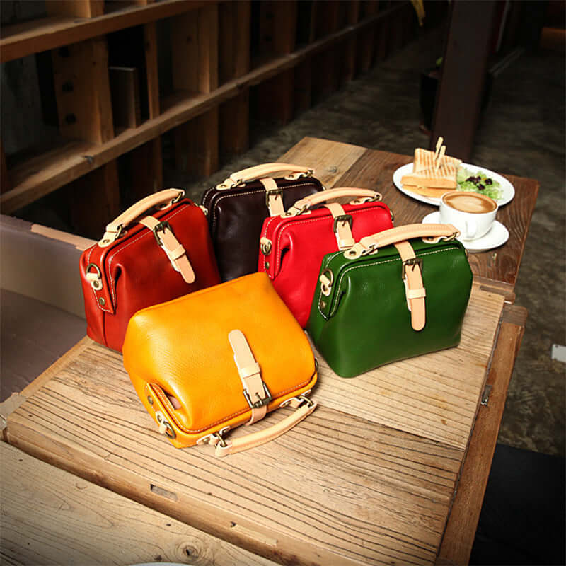 Five different colored leather bags on a table