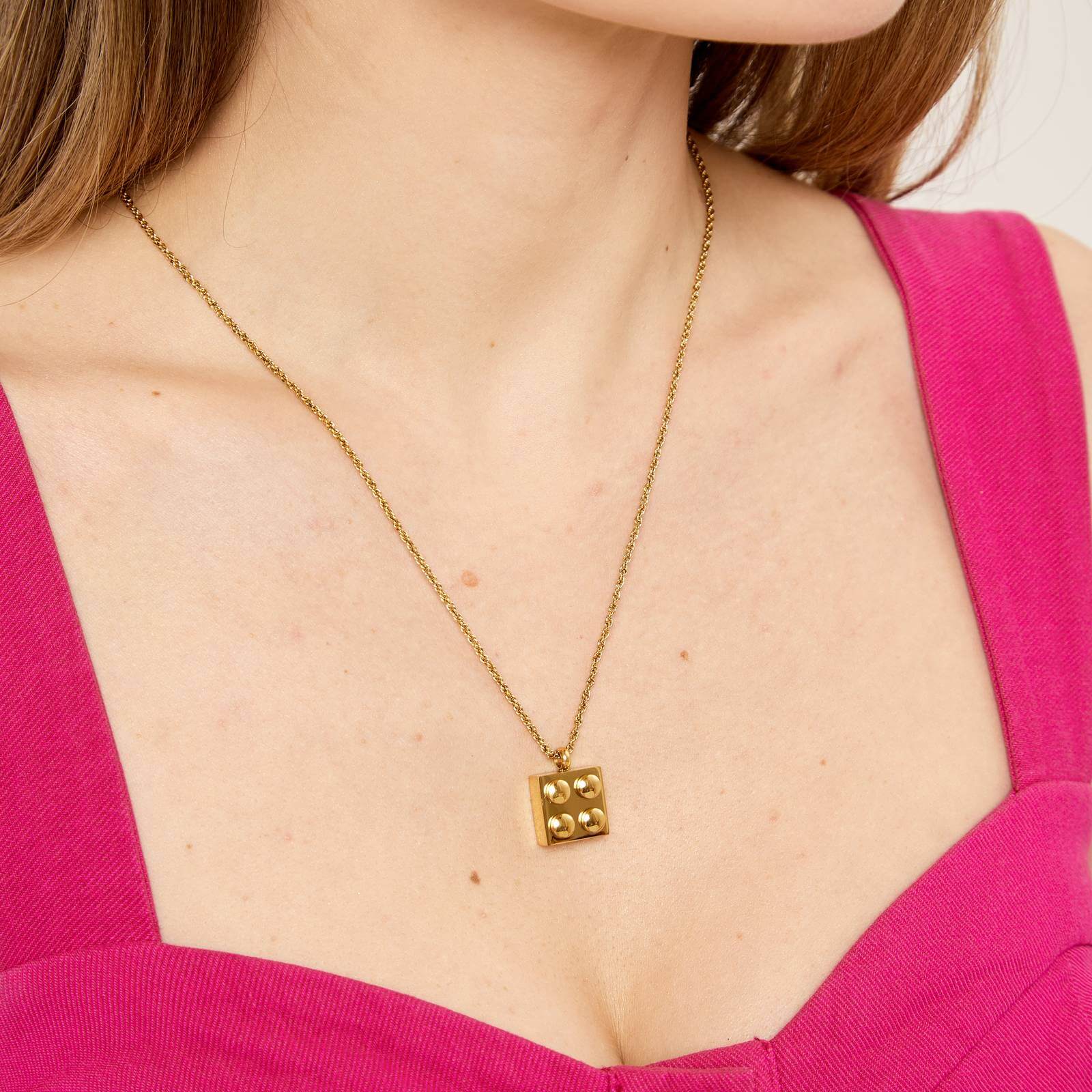 A woman wearing a Gold lego necklace