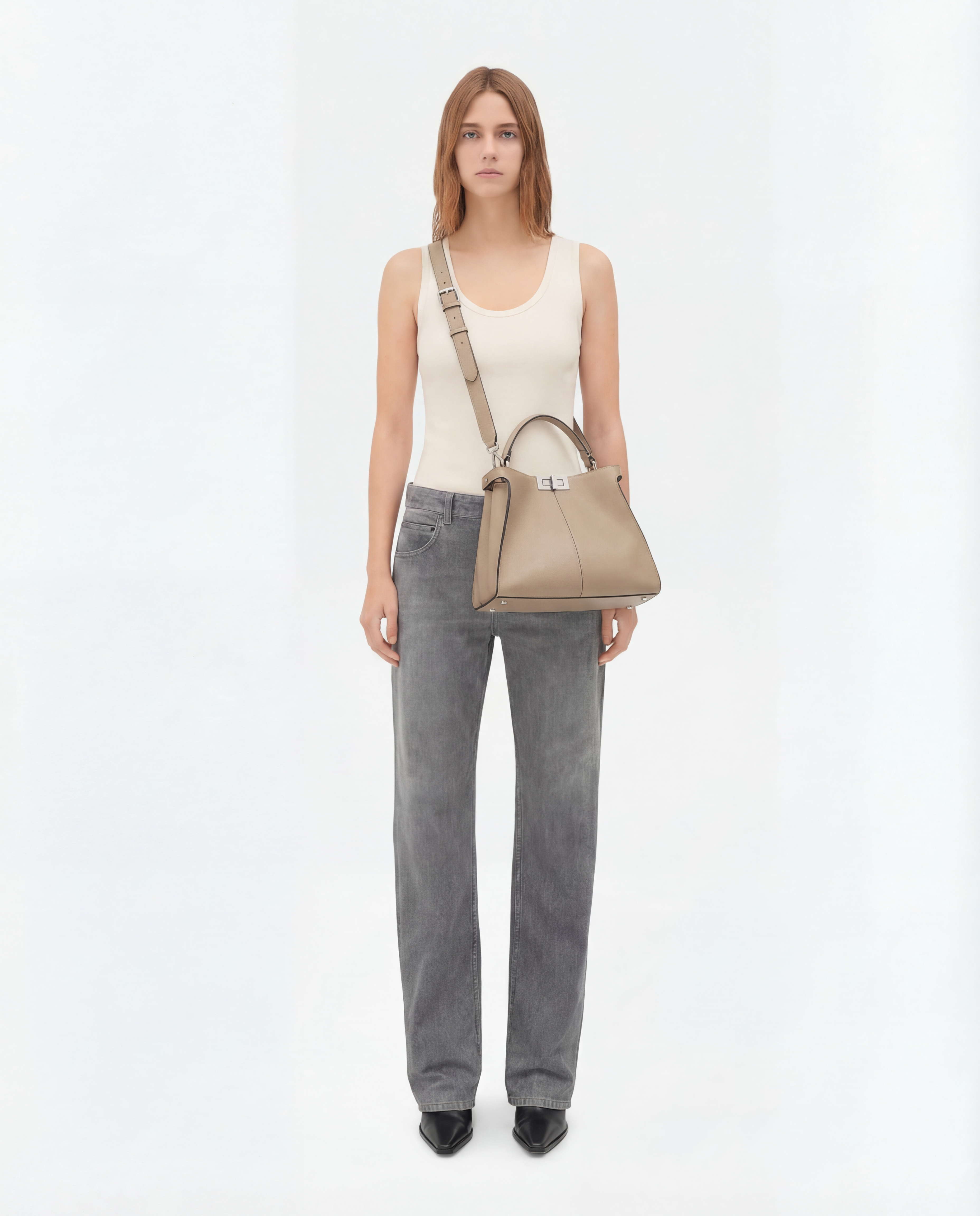 Woman holding a beige handbag against a white background