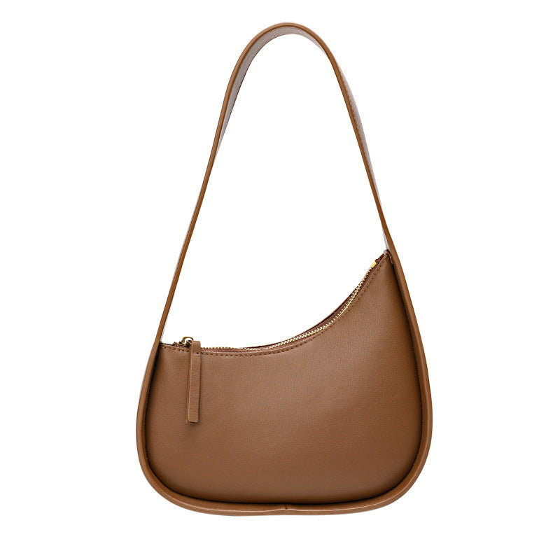 A caramel leather shoulder bag with a half moon design, featuring a wide shoulder strap and a soft handle.