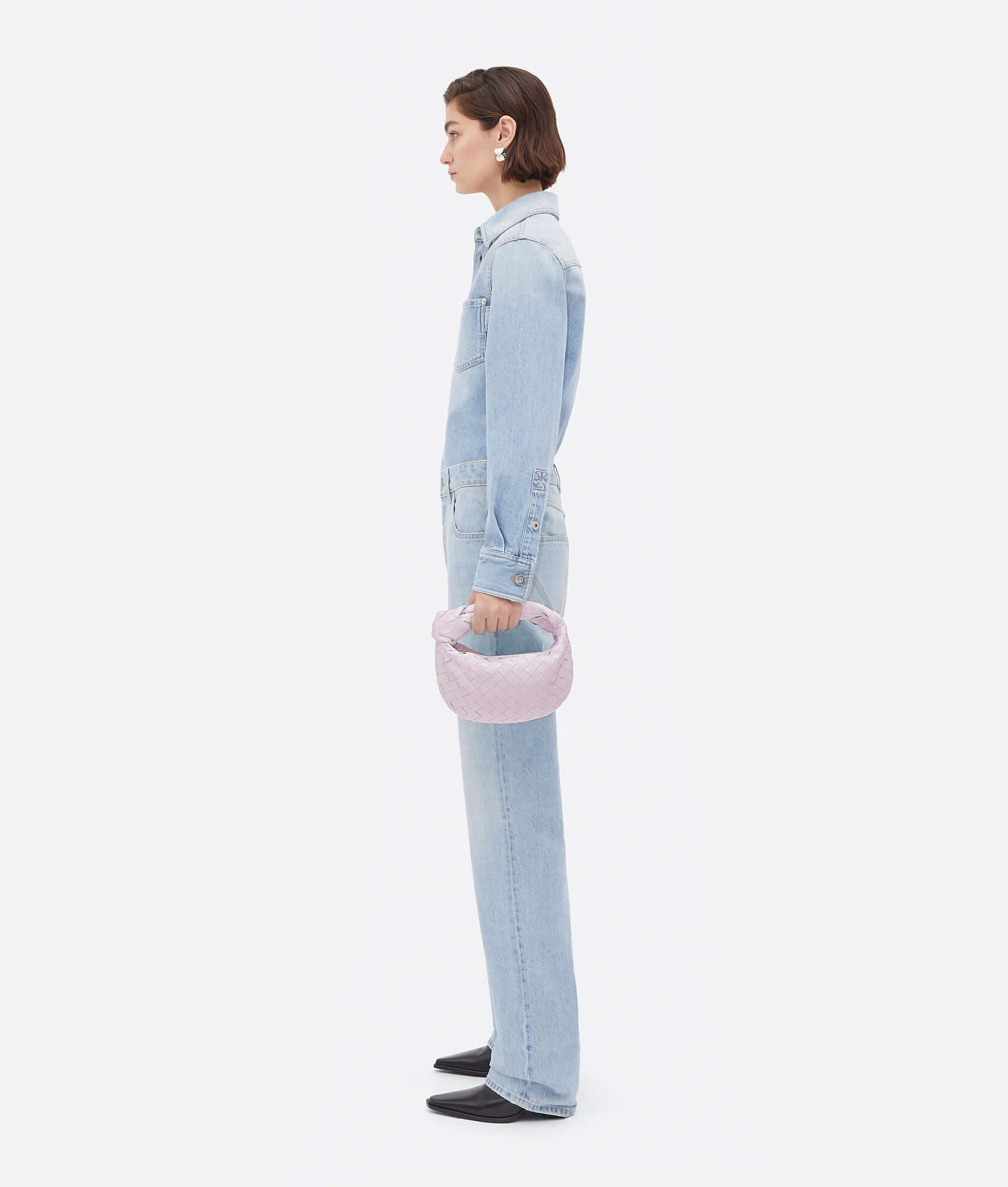 A pink woven handbag inspired by the Bottega Mini Jodie design, featuring a compact and rounded shape.