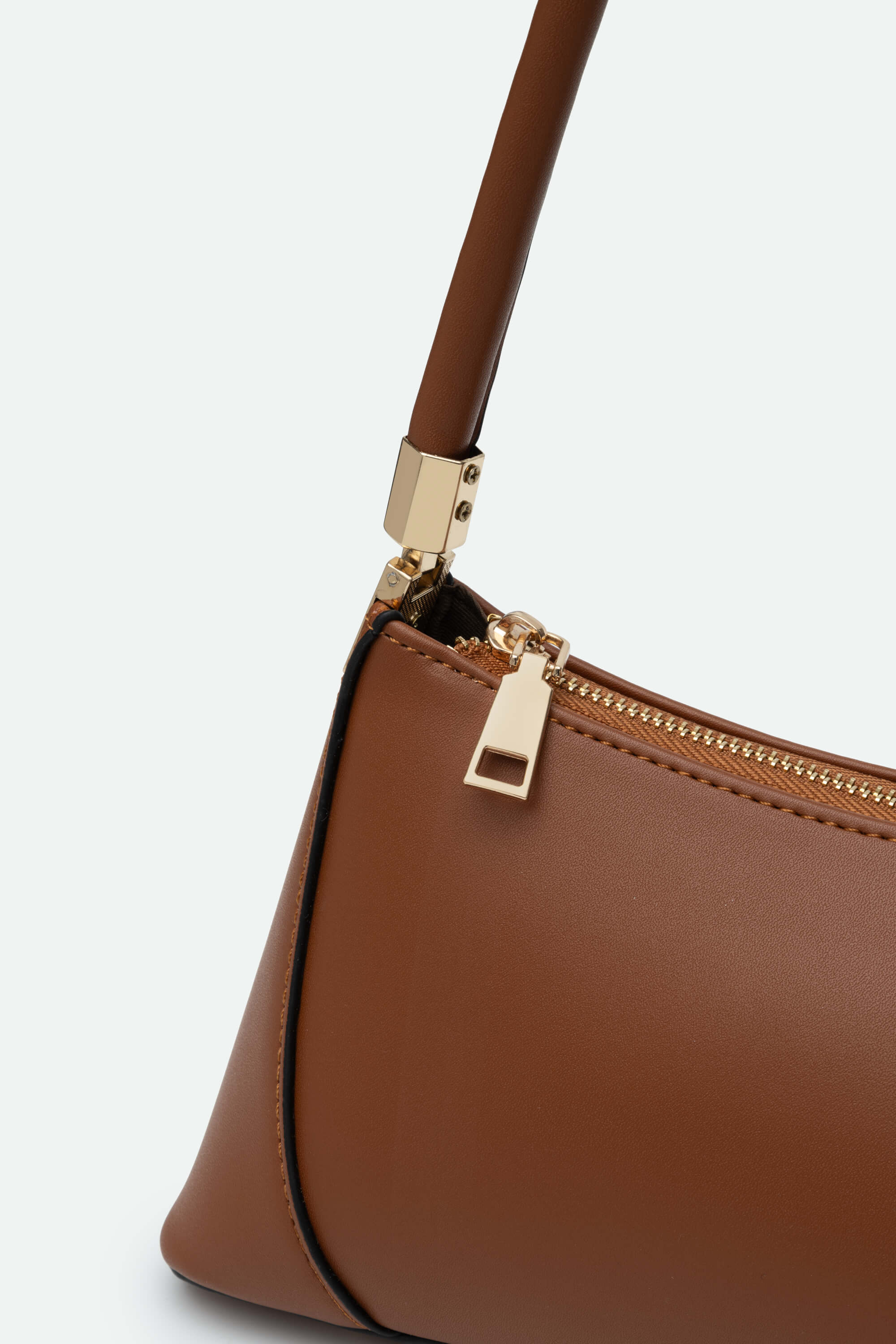 Brown handbag with gold zipper on a light gray background