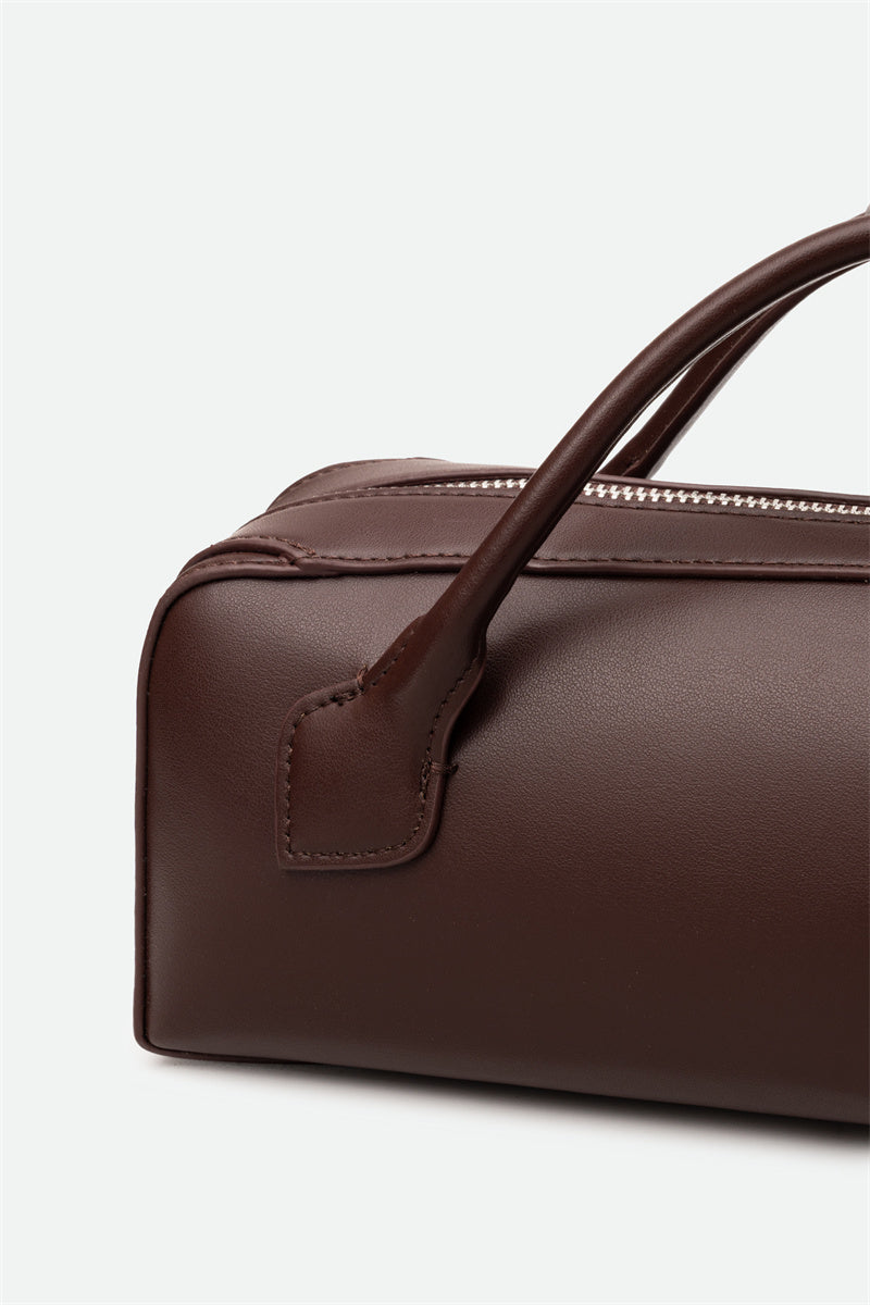 Brown leather handbag with handle on a light gray background