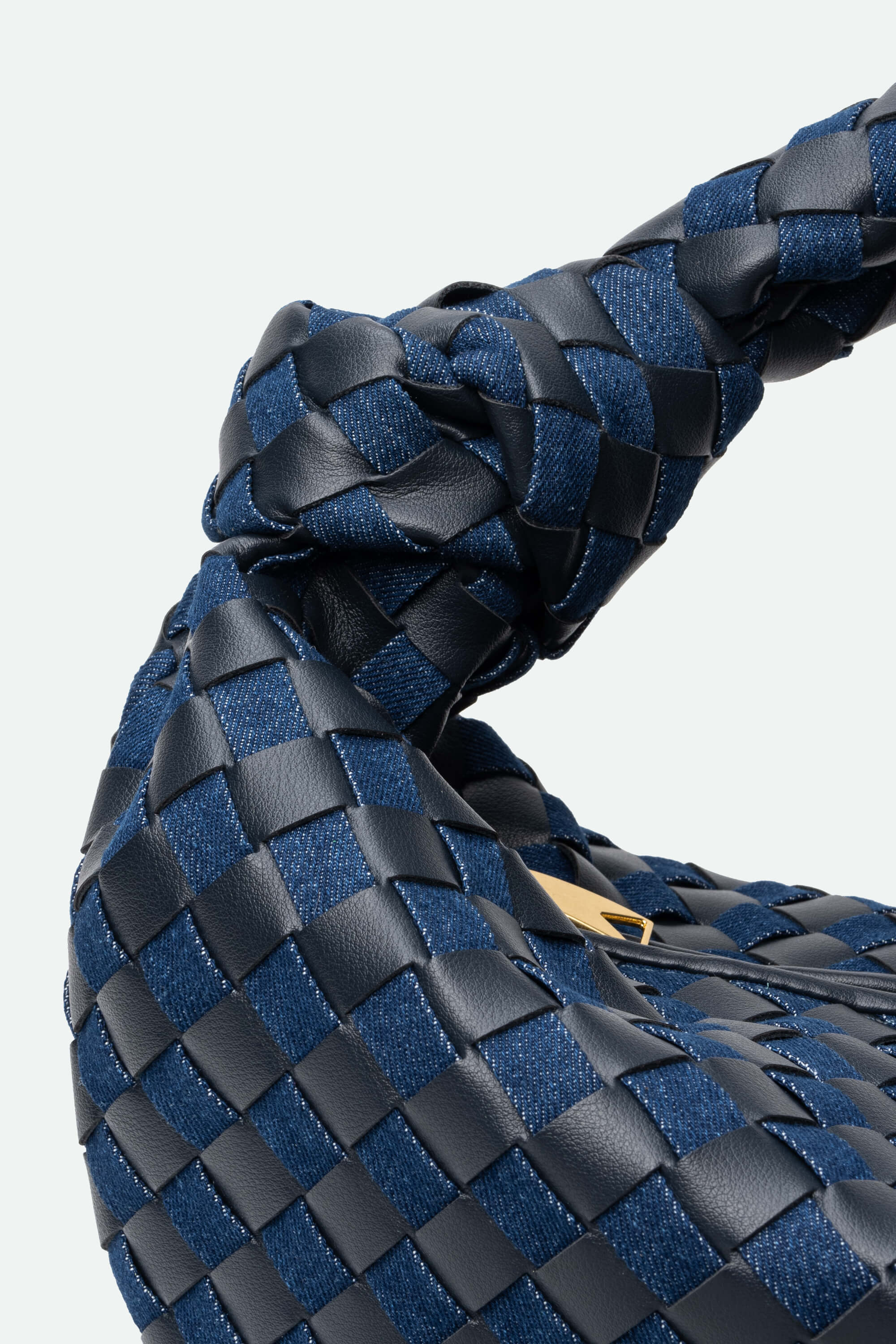 Close-up of a blue and black woven handbag with a visible brand logo.