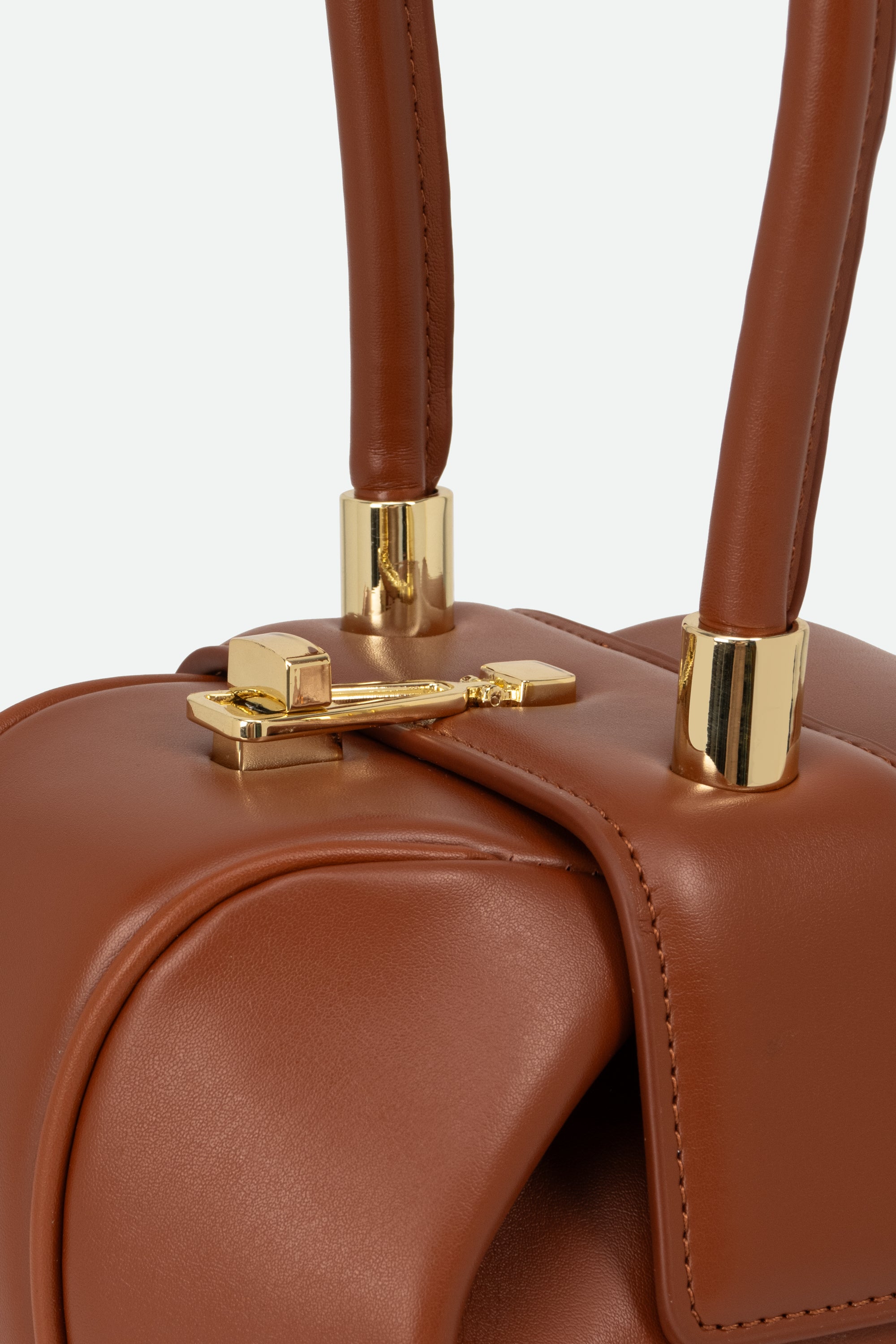 Close-up of a brown leather handbag with gold hardware on a light gray background