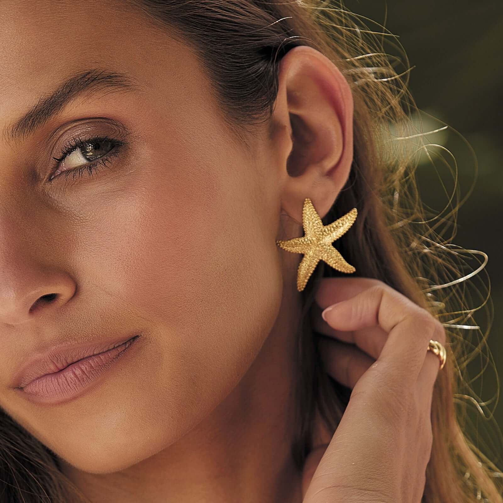 A woman showing her gold starfish shaped earring