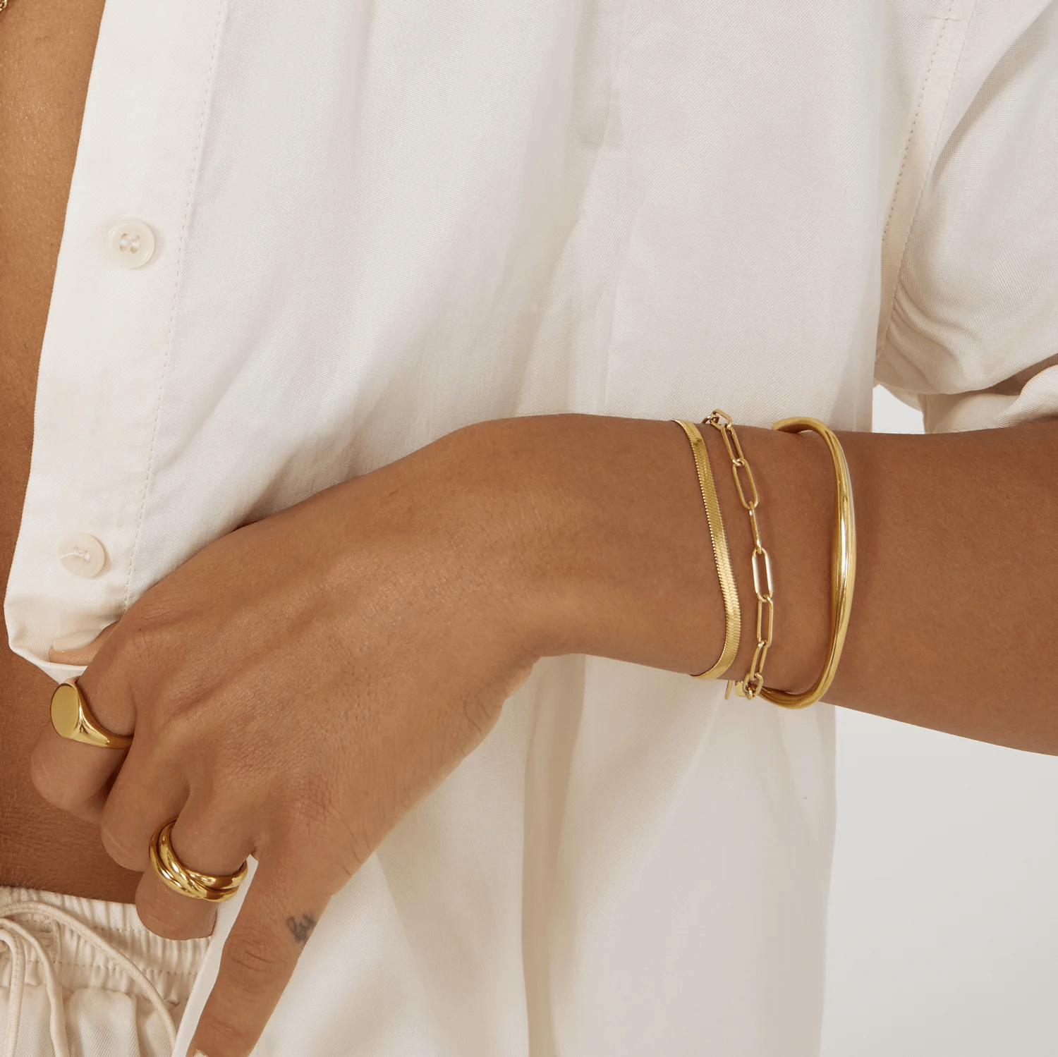 A model wearing Gold snake chain bracelet stacks