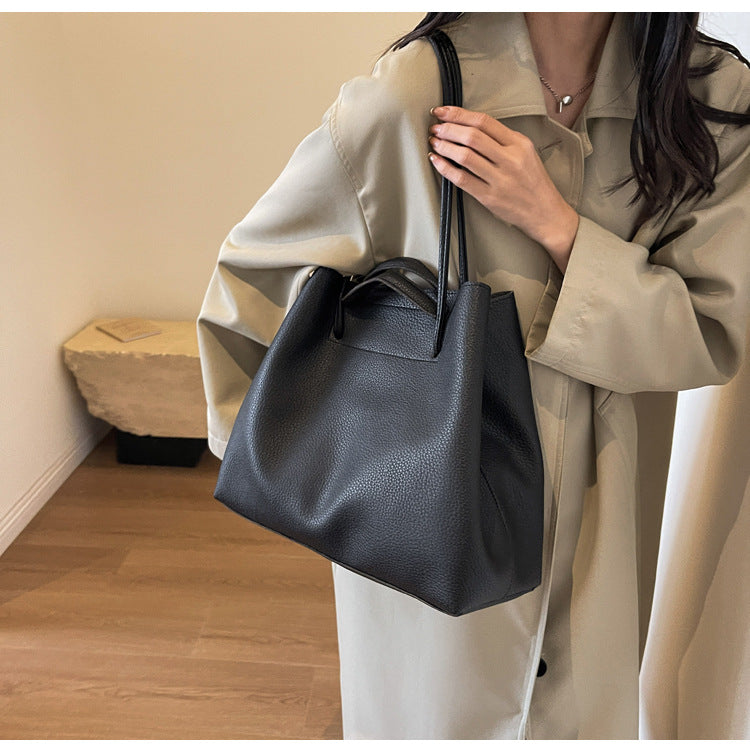 Person holding a black leather handbag indoors